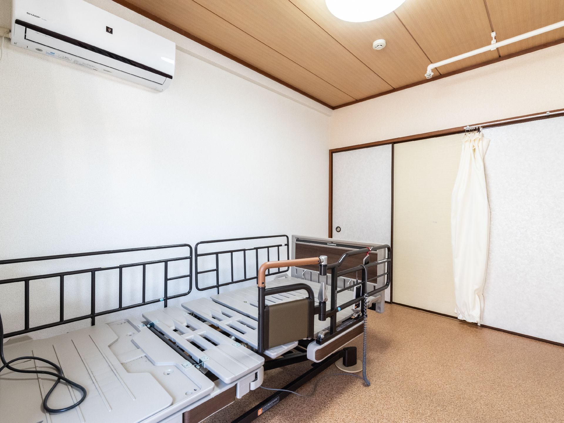 車いすの高齢女性と手を取り合っているピンクのエプロンを付けた女性スタッフ。