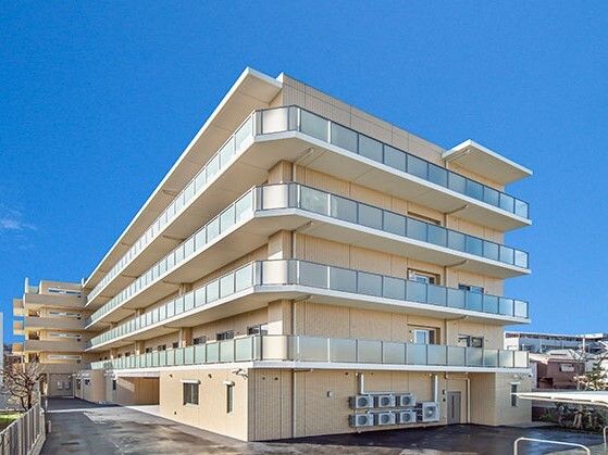 5階建ての建物は日当たりのいい場所に建っている。各フロアにベランダがあり、建物の周りにはフェンスがある。