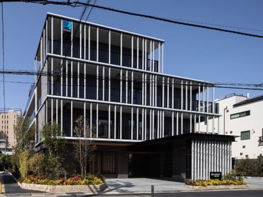 5階建ての建物は壁面がガラス窓となっている近代的なデザイン。建物の周辺には緑もたくさん植えられている。