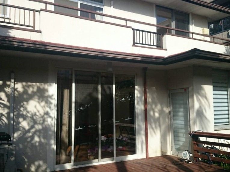 ウッドデッキのテラスが１階部分についた２階建ての建物。２階部分にはバルコニーもある。