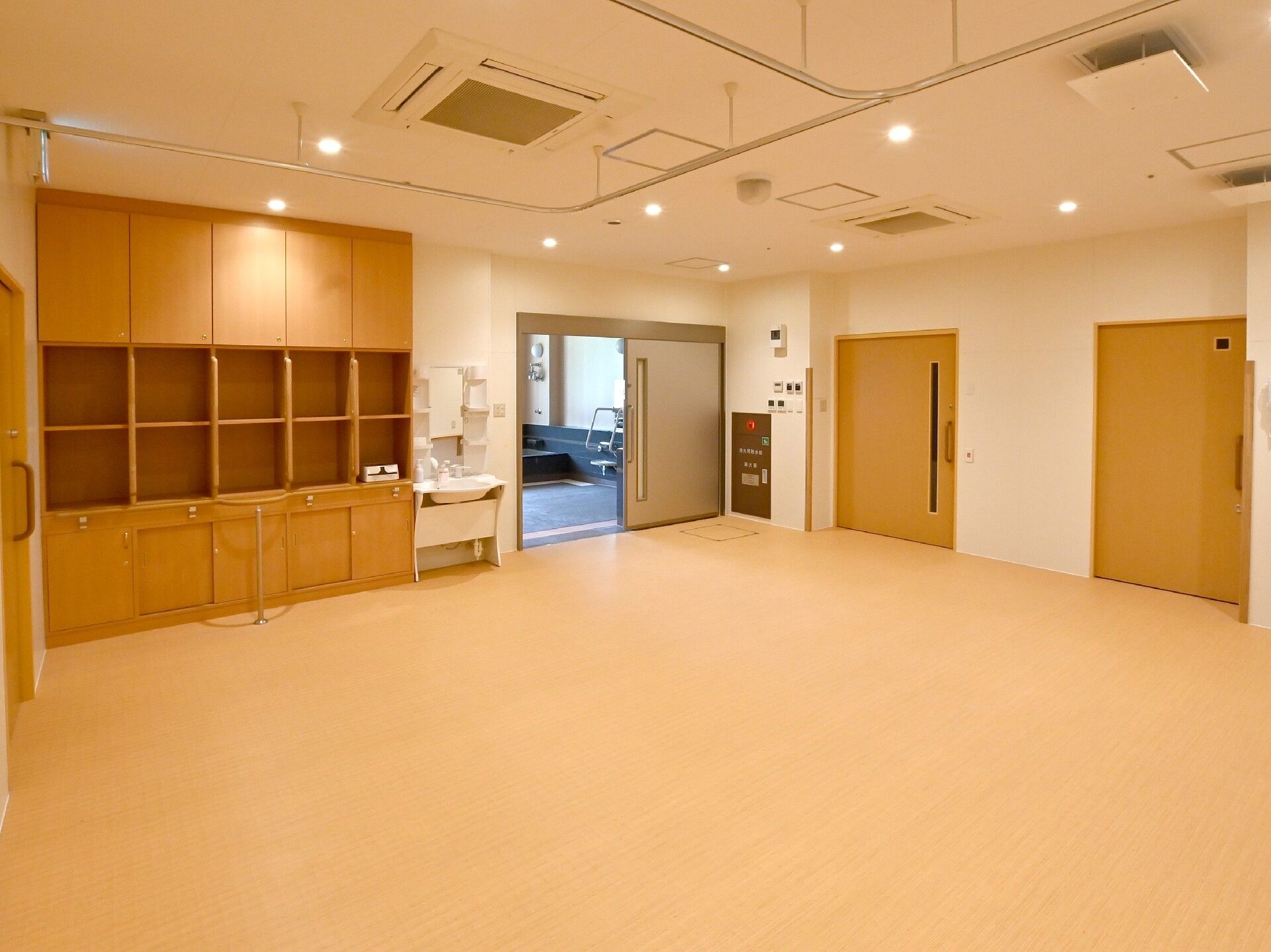 広々とした脱衣所には棚や洗面所が付き、スライド式のドアが複数ある。その内の一つが開いていて浴室内が見える。