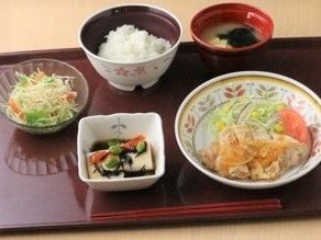 眼鏡をかけた車いすの男性入居者と女性スタッフが屋外での散歩を楽しんでいる。