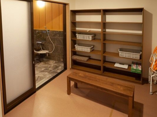 大きなスライド式のドアが付き、右側には脱衣所、左側に浴室があり、脱衣所にはベンチや棚もある。