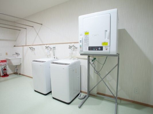 縦型の洗濯機や乾燥機が置かれた広い洗濯スペースには消火器が置かれ、手洗いができる場所もある。