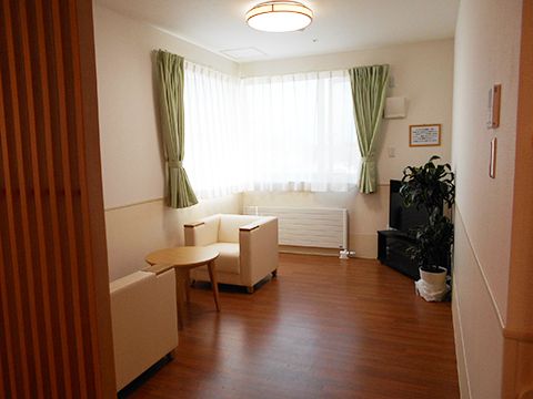 大きな窓が付いたフローリングの部屋にはテーブルセットやテレビ、パネルヒーターが設置されている。