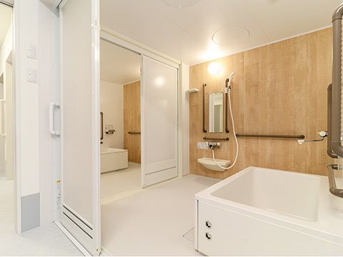 ブラウンの手すりが設置された木目調の壁。一人用の浴槽が設置された個浴が二つ並び、行き来ができる。