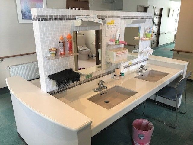 歯ブラシや洗剤、ソープなどが置かれた洗面所。白いタイル張りの壁には黒いタイルでアクセントが付いている。