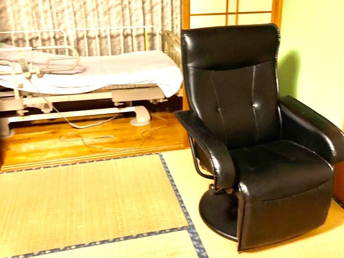 居室にフットレスト付きの黒い皮の椅子が置かれている
