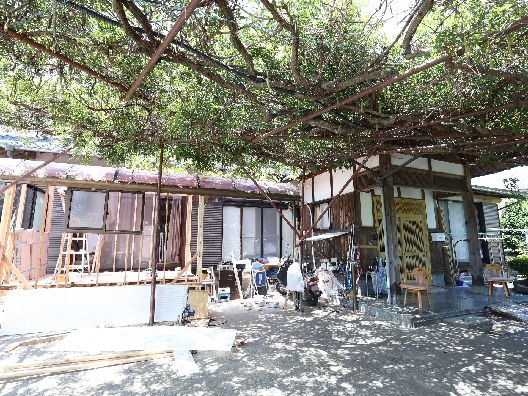 木が絡まることができる棚が設置され、木陰が作られている庭。椅子なども置かれている。