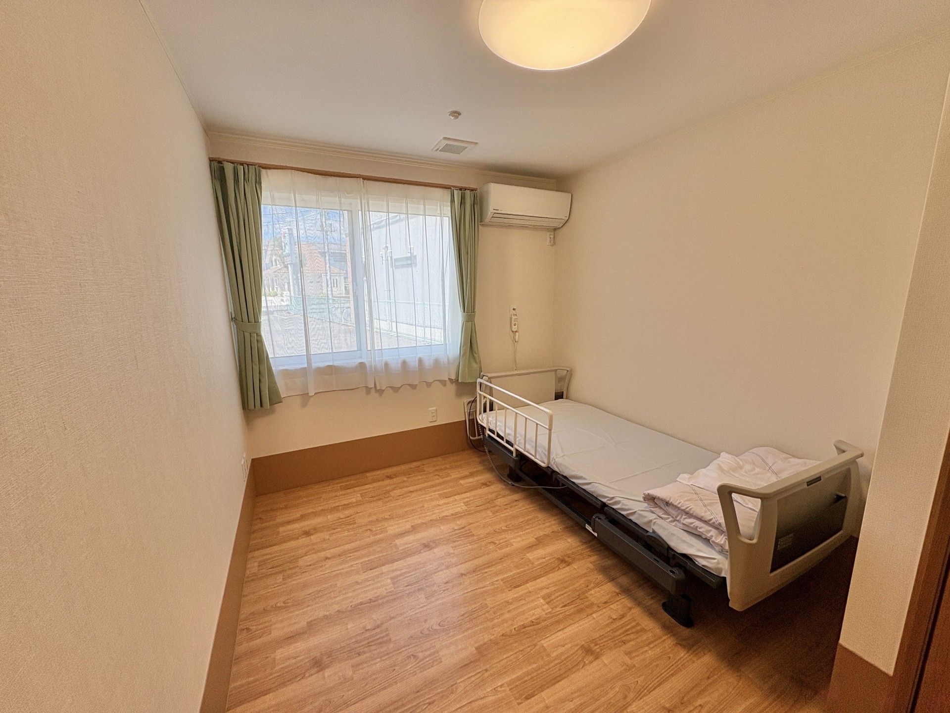 屋外の福祉車両のそばでほほ笑み合っている車いすの高齢女性とピンクのエプロンを付けた若い女性スタッフ。