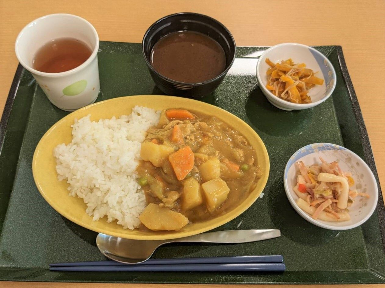 カレーライスに味噌汁、切り干し大根などが並んだ黒いトレーには箸とスプーンも置かれている。