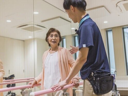 外出イベントを楽しむ車いすの高齢の男性入居者。女性スタッフが笑顔で付き添っている。