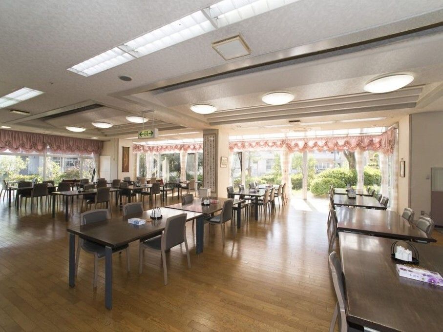 木製のダイニングテーブルが複数置かれた食堂の壁一面が窓となっていて、外の庭園を眺めることができる。