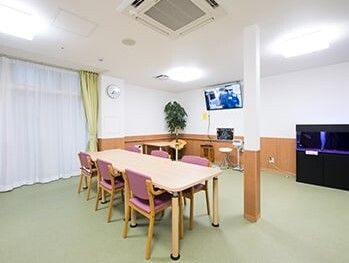 ６人掛けのダイニングテーブルが置かれたスペース。奥にはテレビや観葉植物もある。