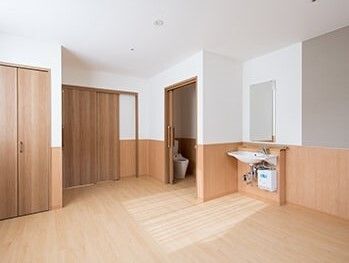 トイレと車いす対応の洗面所、収納スペースが付いたフローリングの居室。家具などは置かれていない。