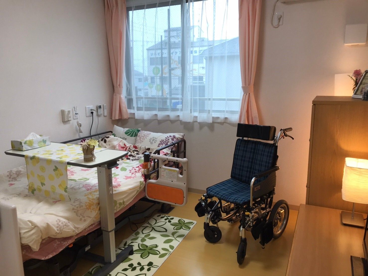高齢夫婦と若い女性が芝生の上で話をしている様子。3人とも笑顔で座っている。