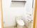 温水便座のトイレが置かれたスペースは広く、床下収納もある。便座の上には収納棚があり、壁には呼び出しボタンも付いている。