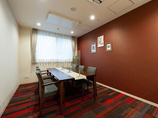 暖色系のインテリアで、六人掛けのテーブルが置かれた窓のある部屋