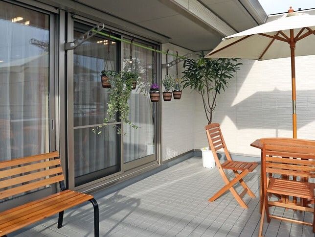 パラソル付きのテーブルセットが置かれたテラスには木製のベンチもあり、観葉植物や緑が飾られている。