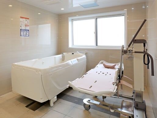 大きな窓が付いたタイル張りの浴室にはストレッチャータイプのリフトがあり、寝たままの姿勢で入浴可能。