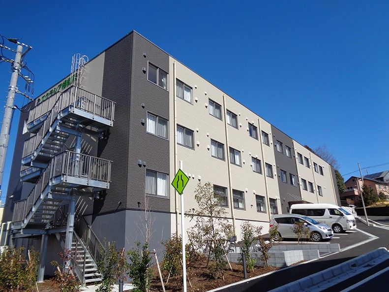 外階段があり、ツートンカラーの外壁の3階建て建築物