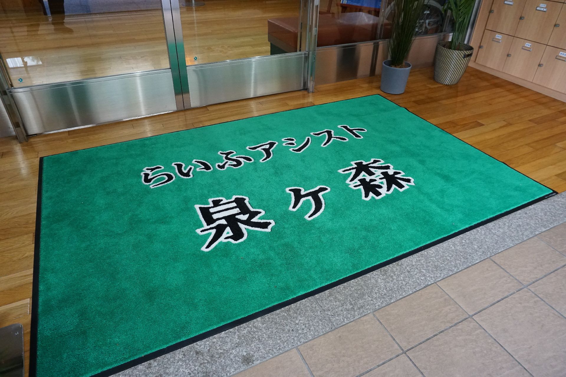 地面に段差が極力なく、マットに施設の名称・ロゴが書かれているエントランス