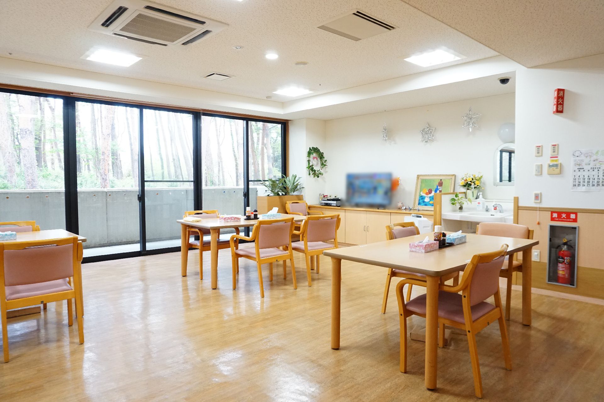 窓から光が差し込み、テーブル、椅子が置かれている共有スペース