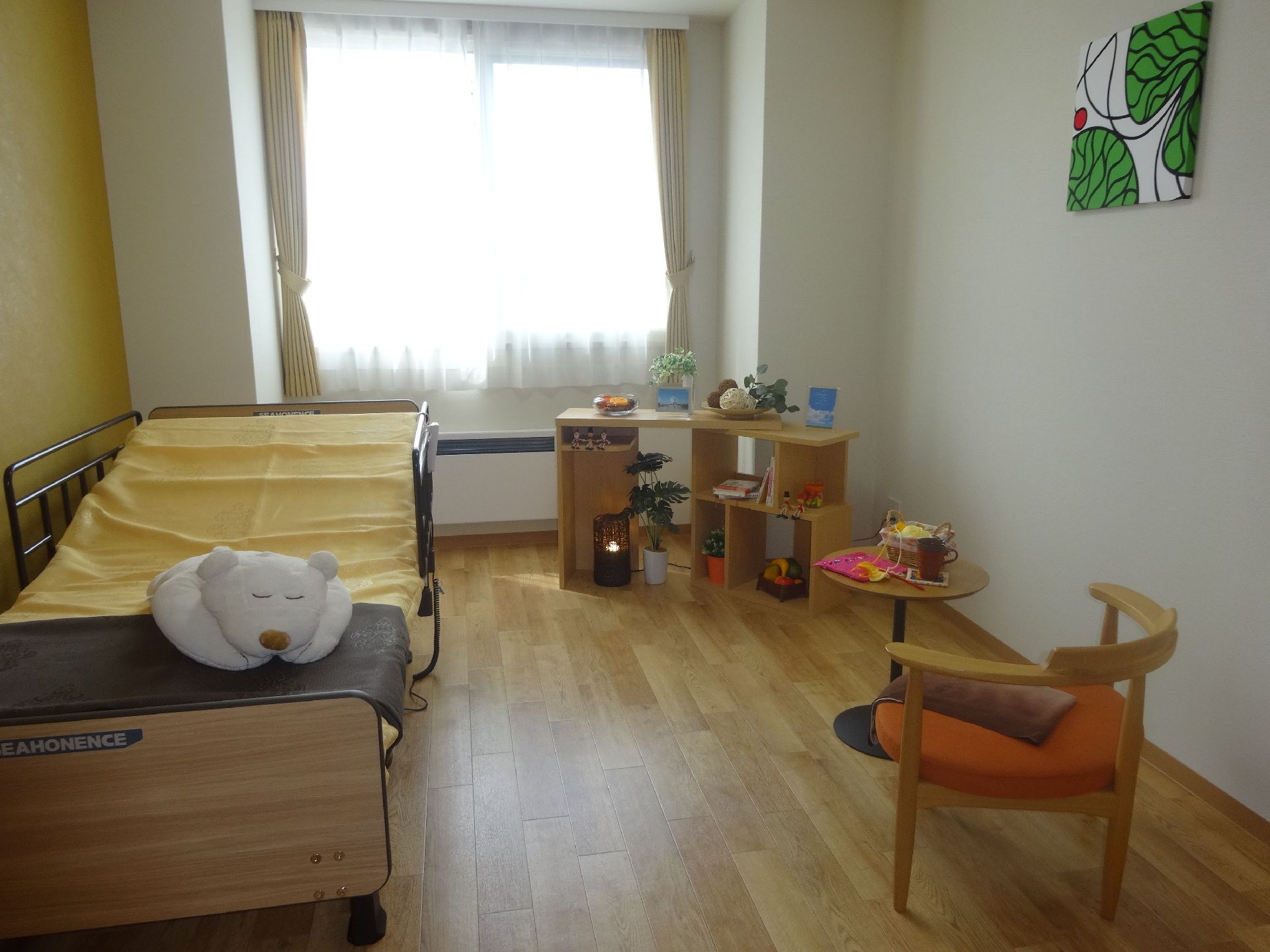 左には介護ベッド、小さいサイドテーブルに椅子があり、大きな窓もついた部屋