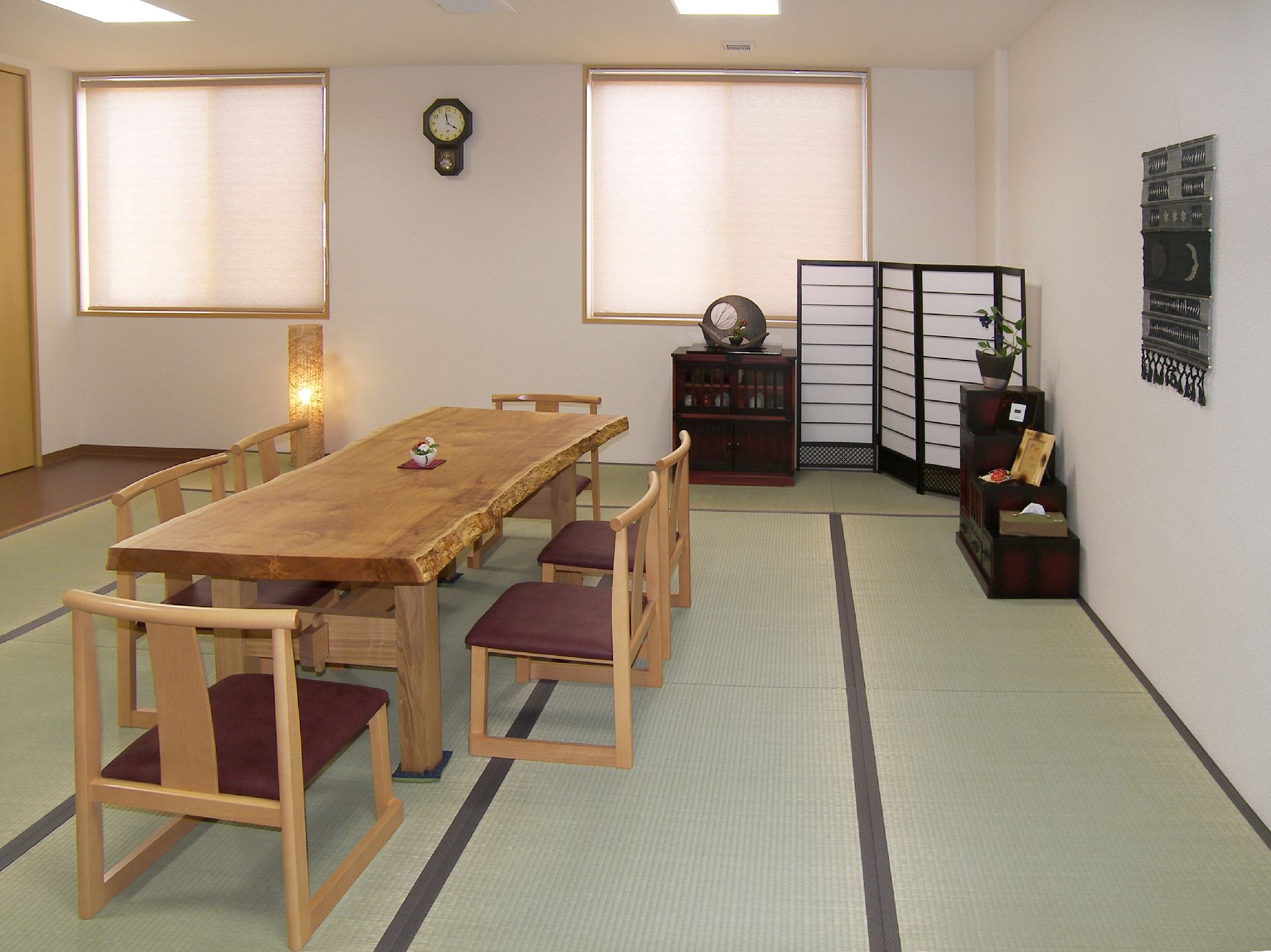 畳の部屋に一枚板のテーブルが置かれた多目的室、和のインテリアが飾られている