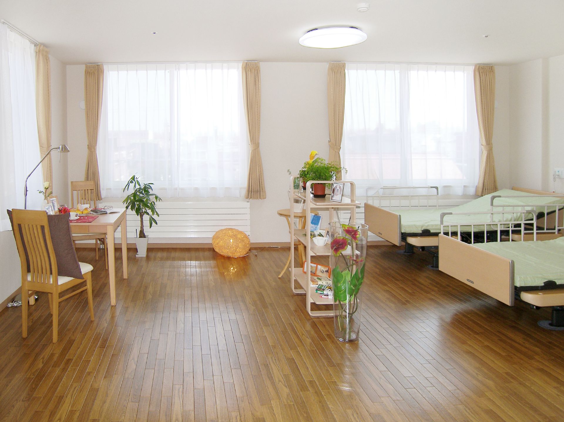 ベッドがみぎがわに二つ置かれている二人用の居室の様子。広めのワンルームタイプの部屋