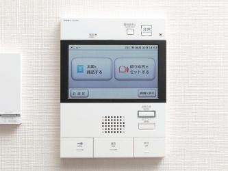 白い壁に設置されたモニター付きインターホン。一つひとつのボタンが大きく、イラスト入りなのでわかりやすい。
