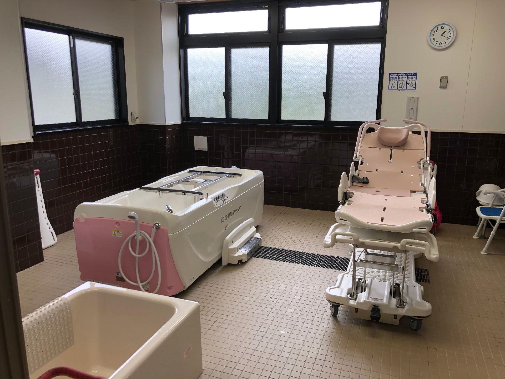 窓がたくさん付いた広い浴室の手前には複数の方向から介助が可能な一人用の浴槽が設置され、奥には寝台浴もある。