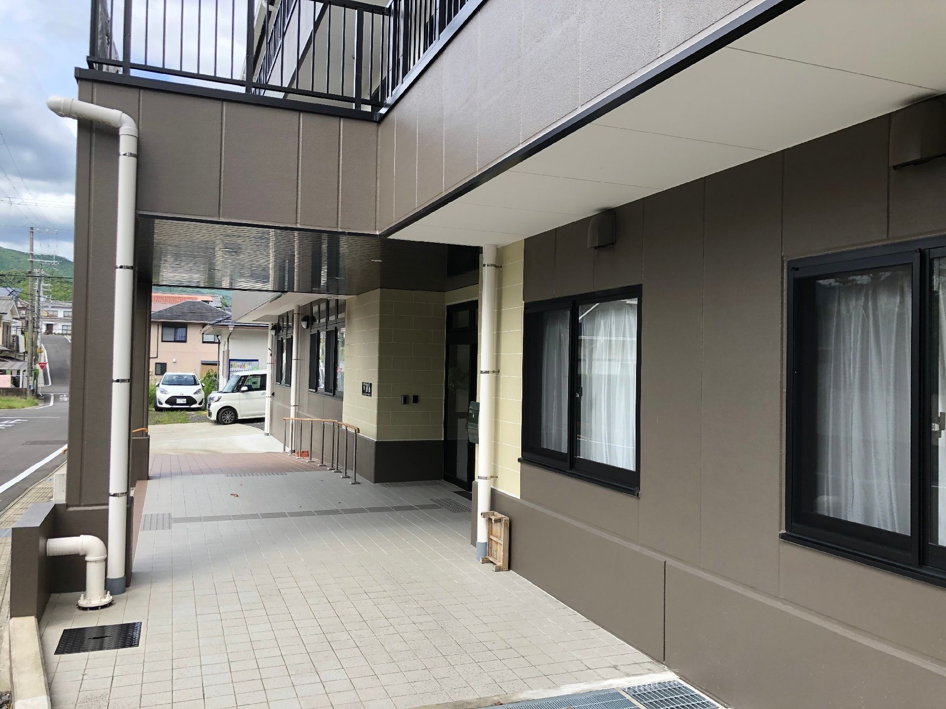 段差はなく、手すりが設置されたエントランス周辺には余計なものがなく、奥には駐車場もある。