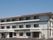 3階建ての建物の前には駐車場があり、白を基調とした外壁。日当たりのいい場所に建っている。