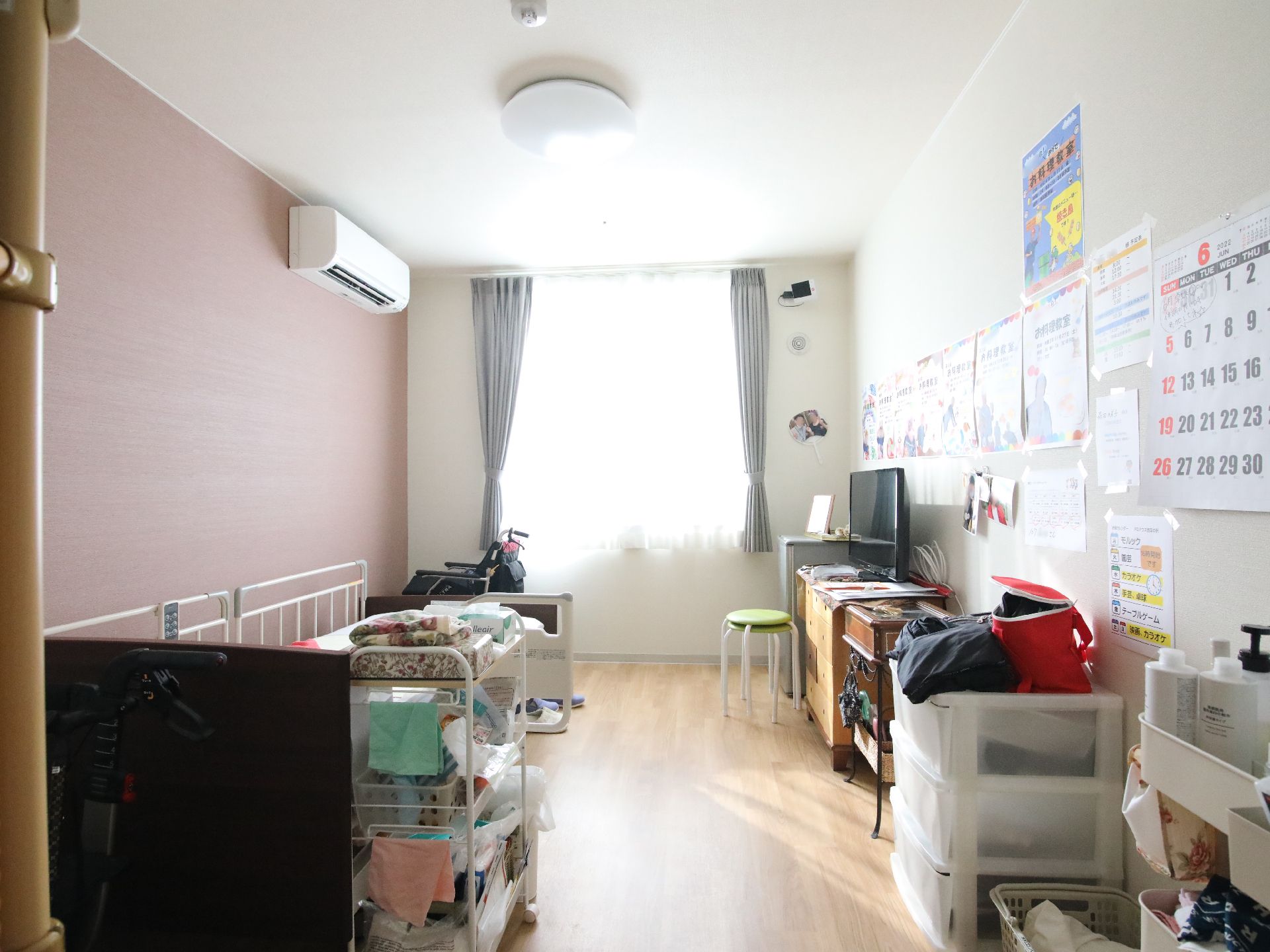 窓から日差しが差し込み、介護ベッドや家具、ペットハウスが置かれている居室