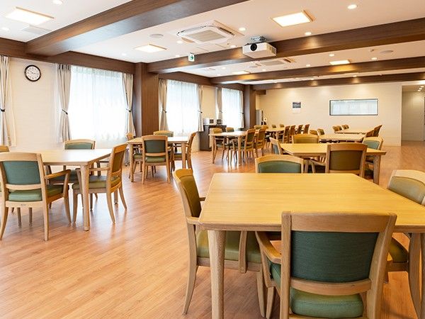 グリーンの椅子とベージュの机の組み合わせが複数ある広い空間