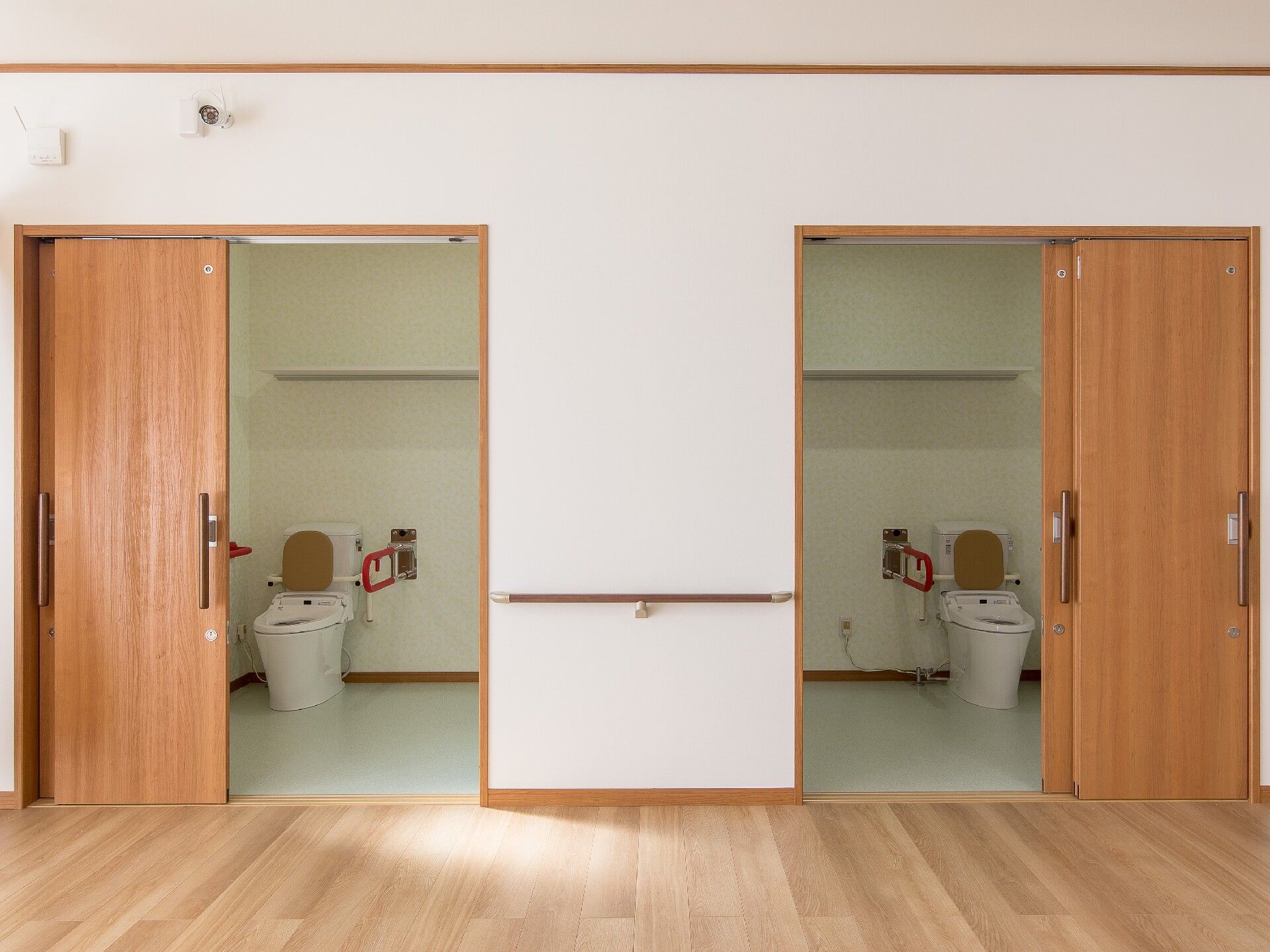 背もたれや手すりが設置された便座が付いたトイレは広く、ドアはスライド式。二つあるトイレは左右対称の造りとなっている。