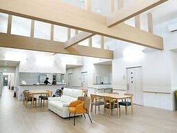 天井の高い平屋建ての建物。対面式のキッチンがあるスペースには木製のテーブルセットやソファが置かれている。