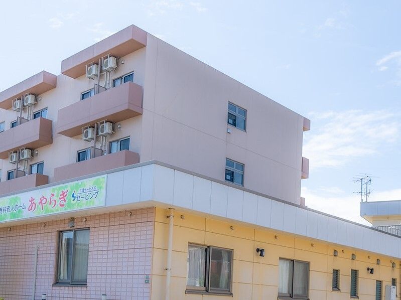 ベランダが付いたブラウン系の建物。ホーム名が書かれた看板が外壁に付いている。