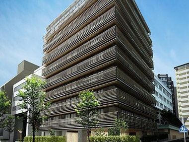 ベッドに寝ている高齢者の女性に話しかけている女性スタッフは、花柄エプロンを付けている。