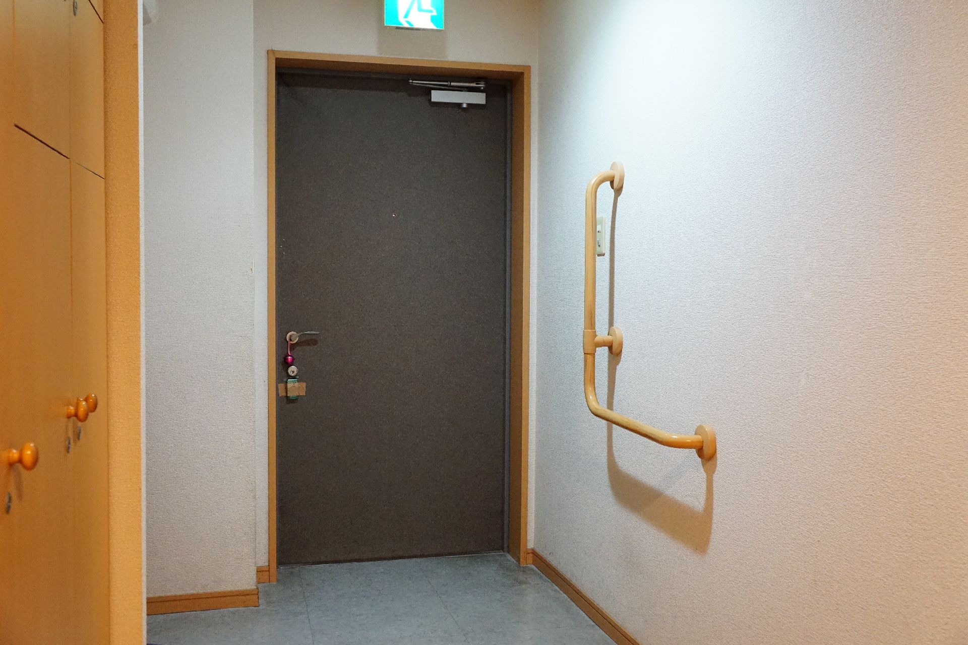 ドアの開閉をしやすいように、壁に大きなL字型手すりが取り付けられている廊下