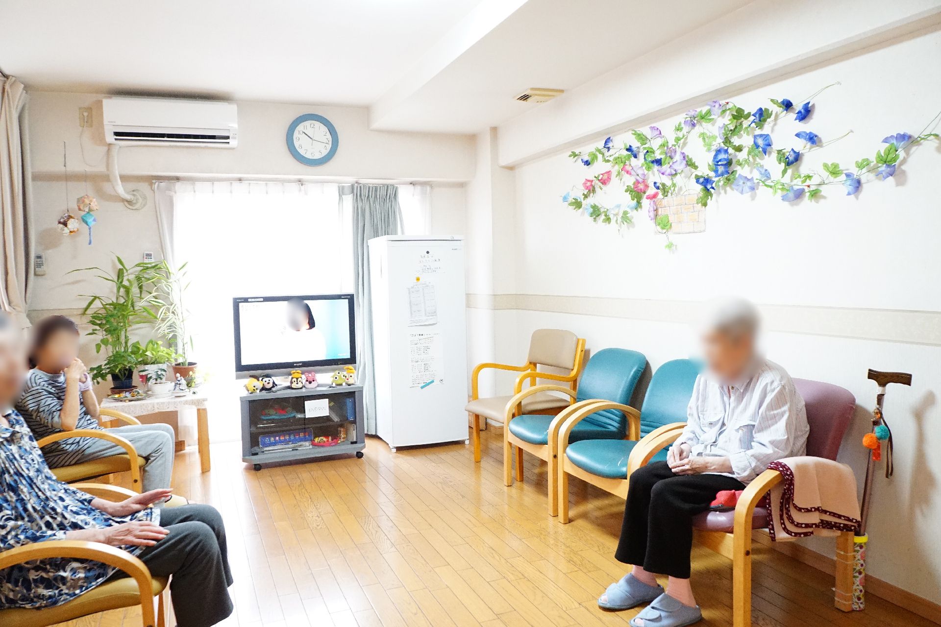 テレビが設置され、入居者が椅子に座って自由に時間を過ごしているリビング
