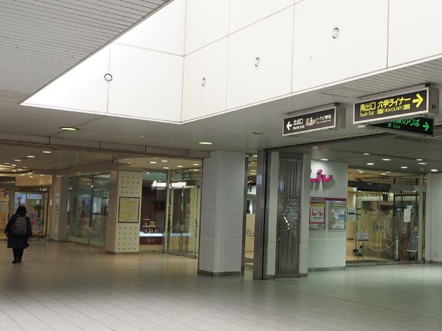 コートを着た人が一人歩いている駅の構内にはまだ開いていないが店もたくさんある。