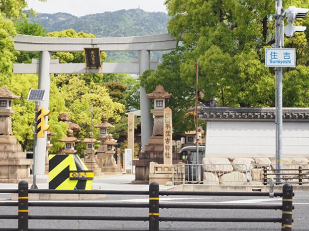 大きな鳥居が設置された神社の入り口。緑も多く、奥には山山も見える。静かな雰囲気で人の姿はない。