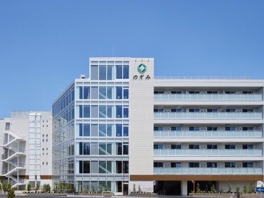 白をメインとした６階建ての建物。建物にはガラス張りとなっている部分もあり、明るくスタイリッシュなデザイン。木も周囲に植えられている。