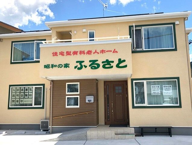 なにかを見て笑顔で手をたたいている高齢女性とスタッフの様子。施設での一場面の写真