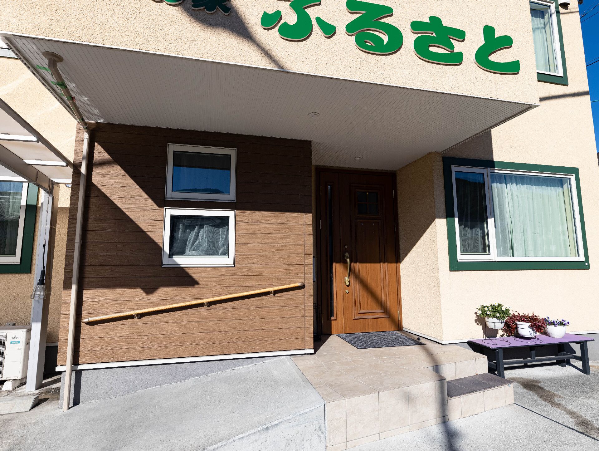 ベンチと花壇が設置された介護施設内にある玄関