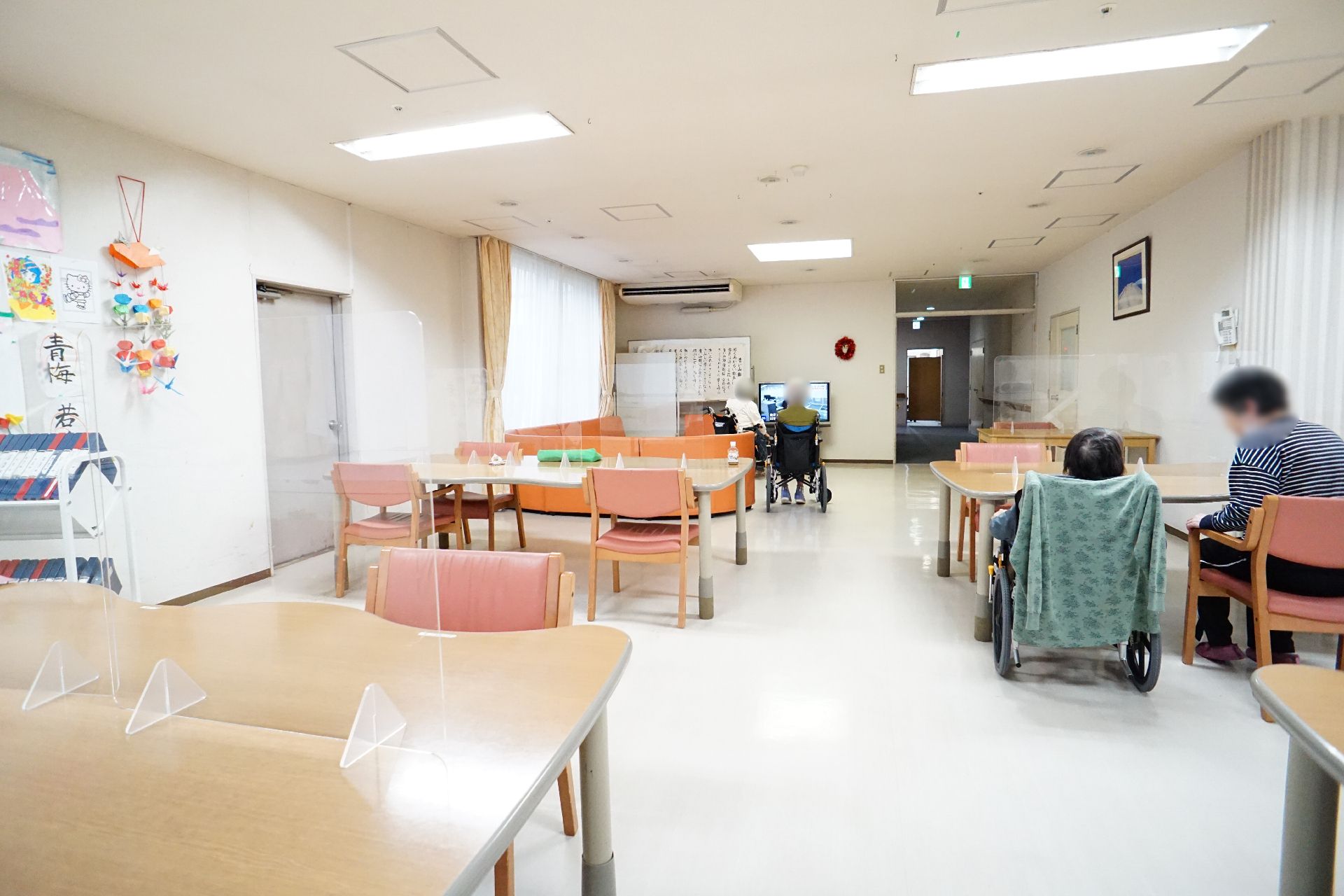輪になってレクリエーションをする高齢女性と女性スタッフ