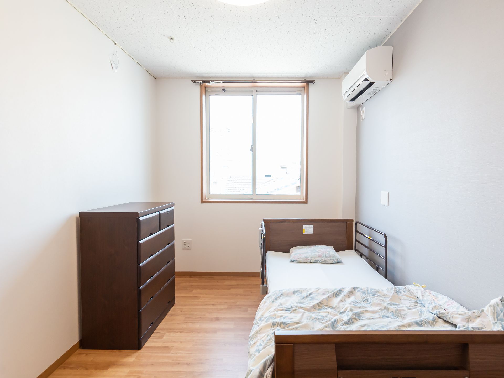 ベッドと黒い棚が配置された白い壁の部屋