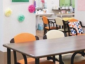木製のテーブルやいすが並べられている施設内のリビングスペースの様子